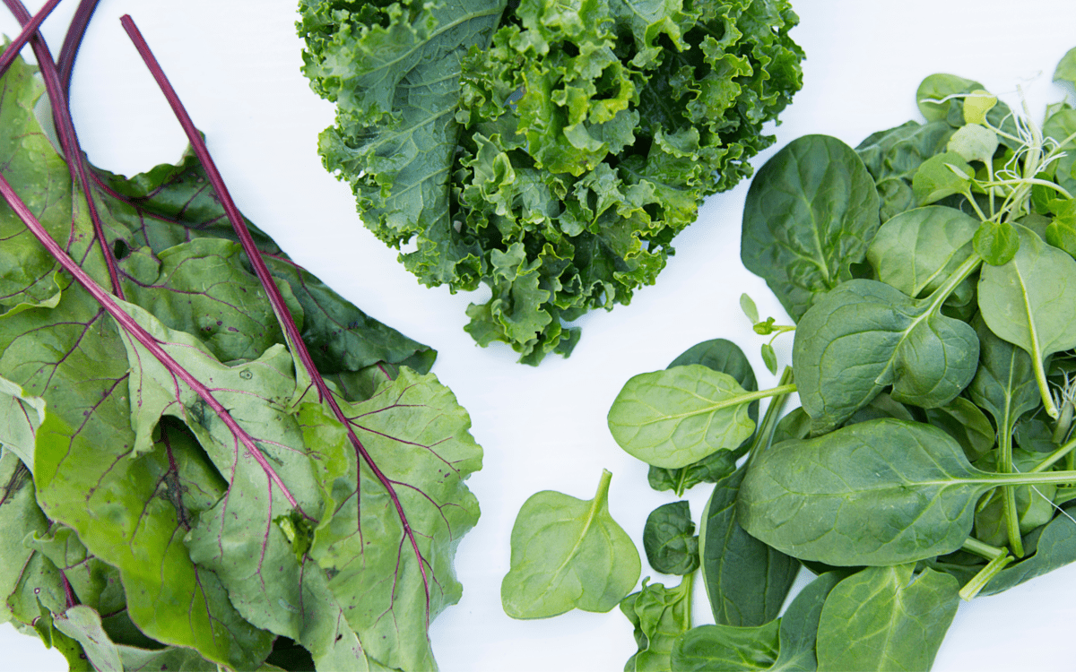 spinach and kale leaves on a table.