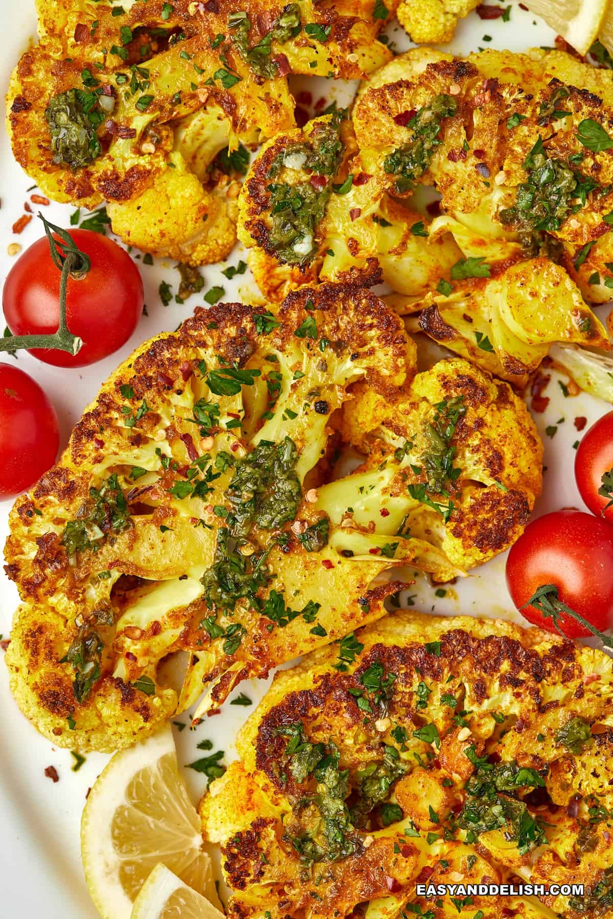 cauliflower steaks with cherry tomatoes and herbs on a platter.