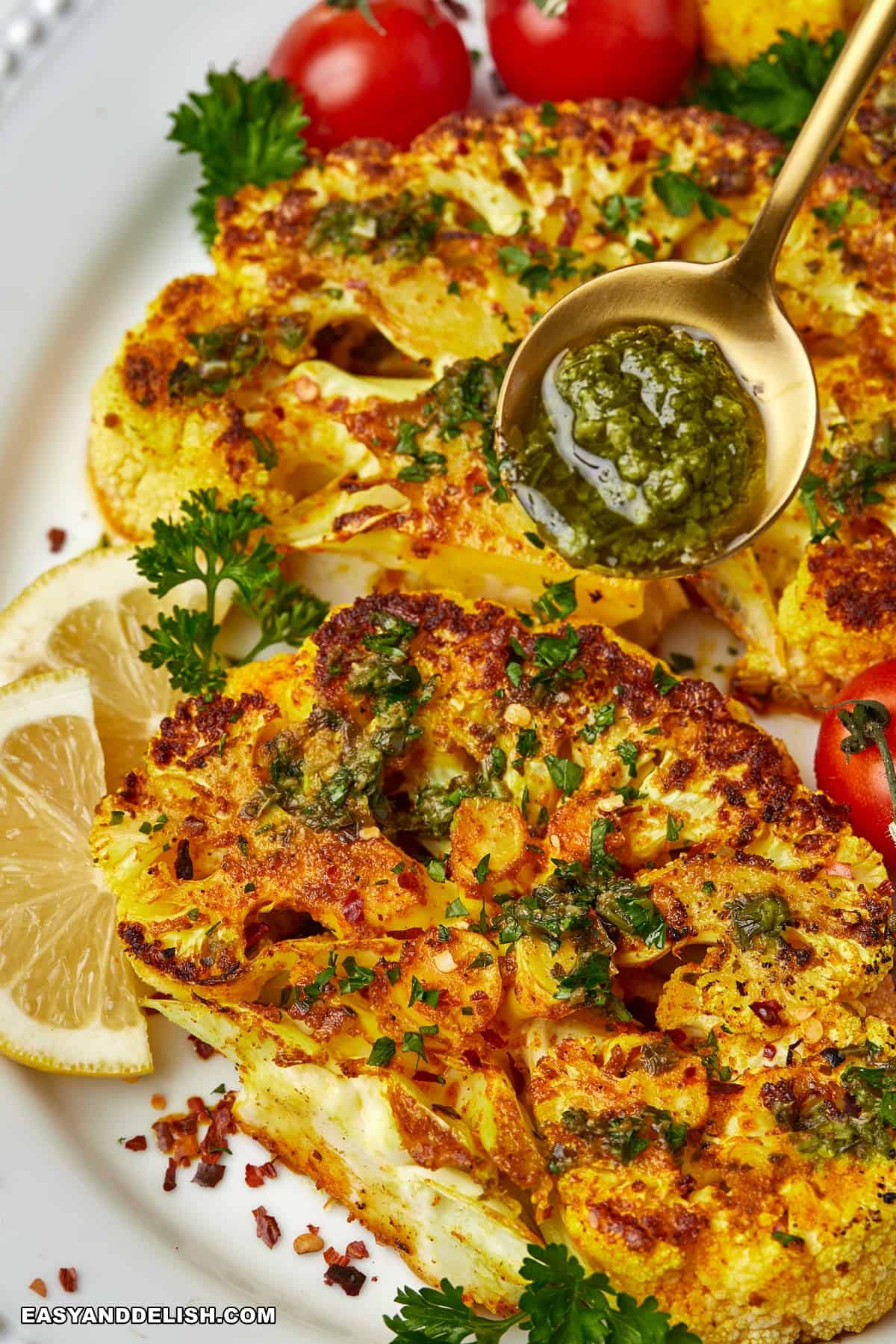 a spoon of sauce spooned over the roasted cauliflower steaks