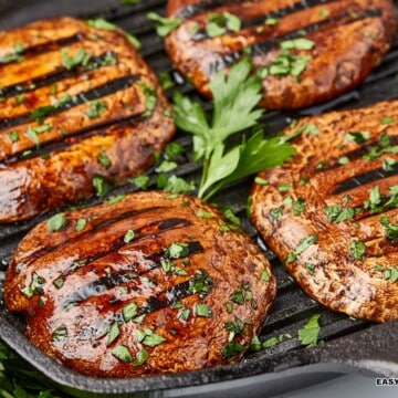 several pieces of grilled mushroom steak topped with sauce and herbs.