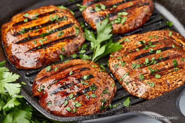 several pieces of grilled mushroom steak topped with sauce and herbs.