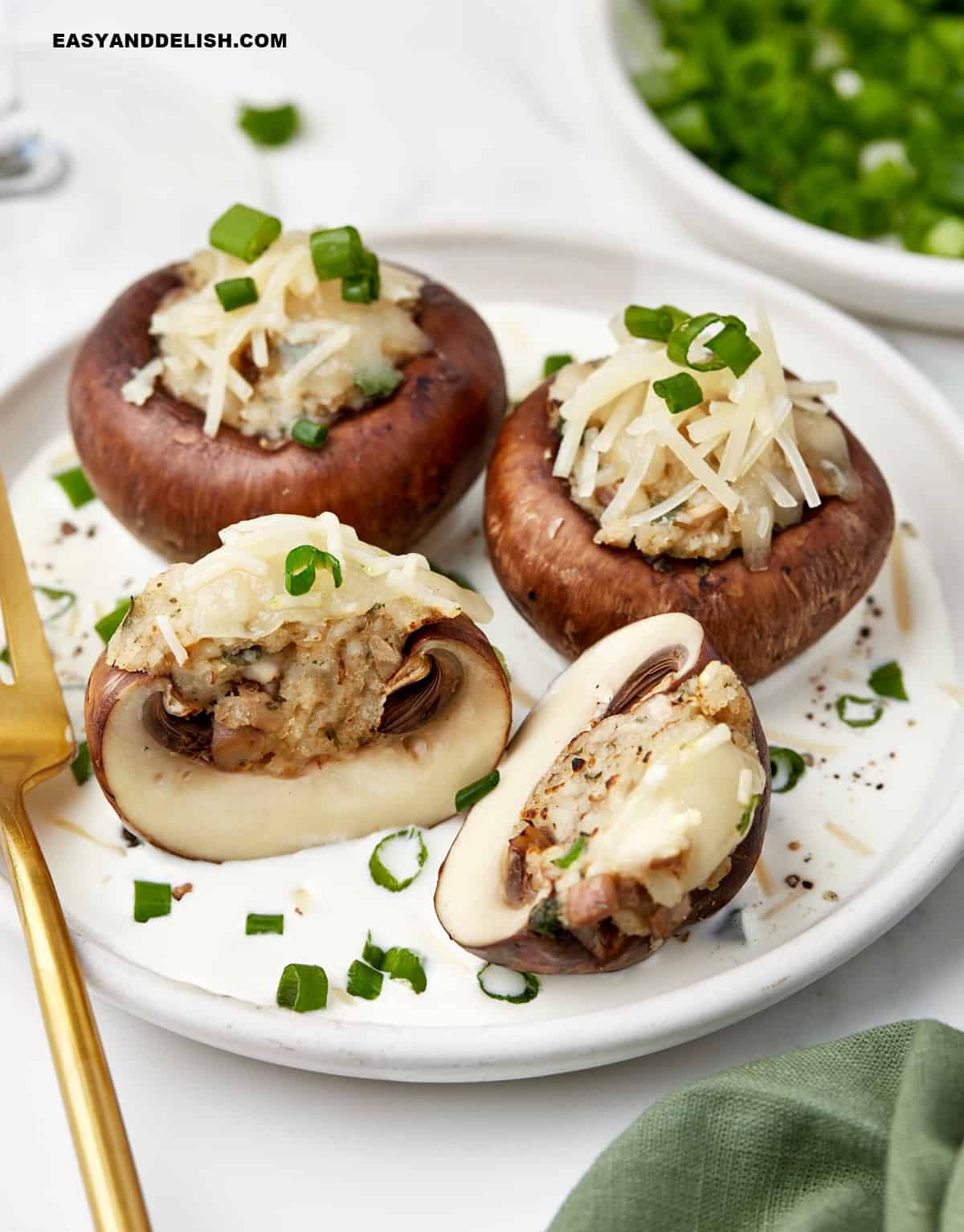 sliced veggies filled with cheese with chopped green onions on top served in a plate.