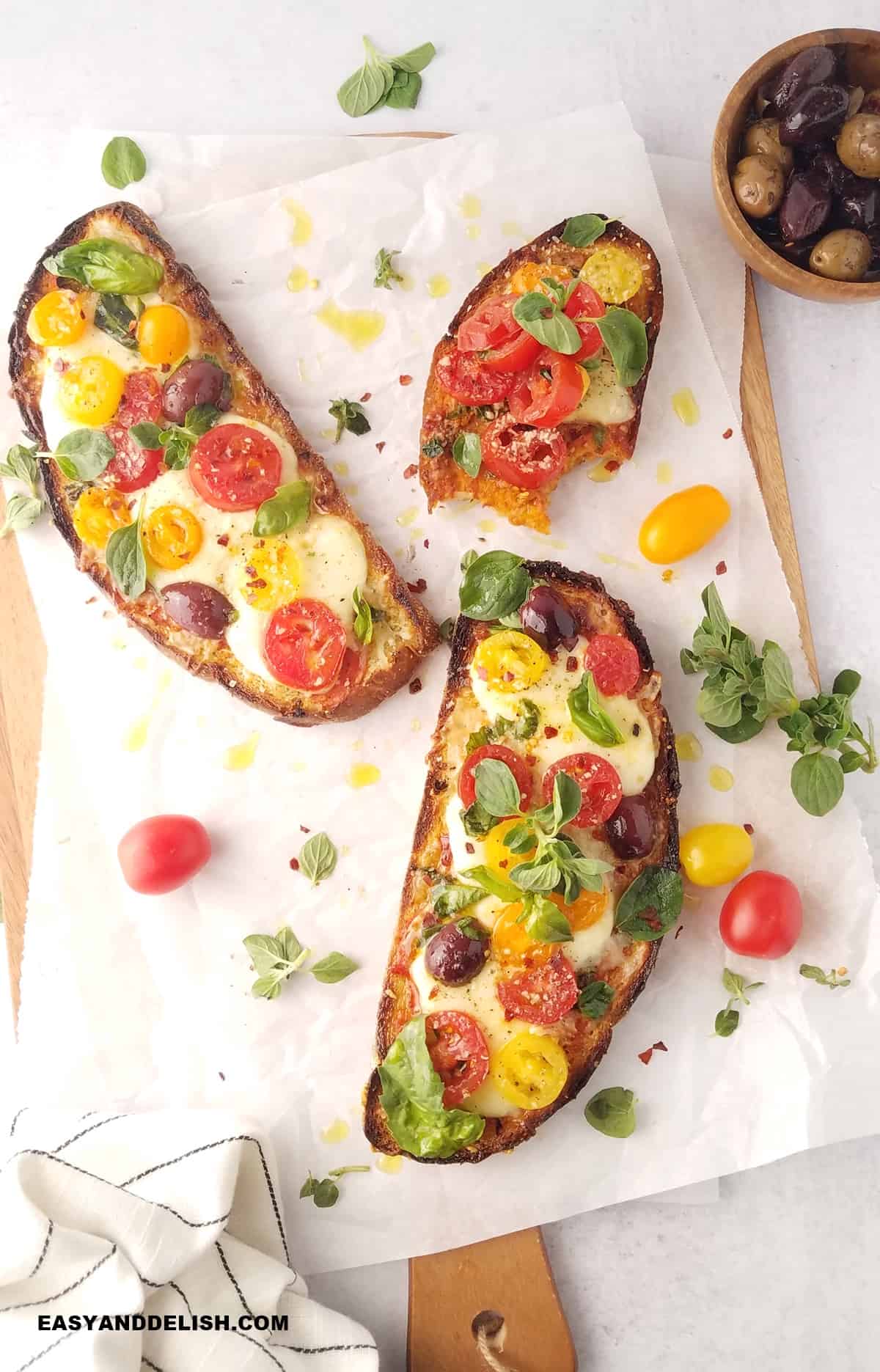 several pizza toasts over a cutting board with garnishes on the side. 