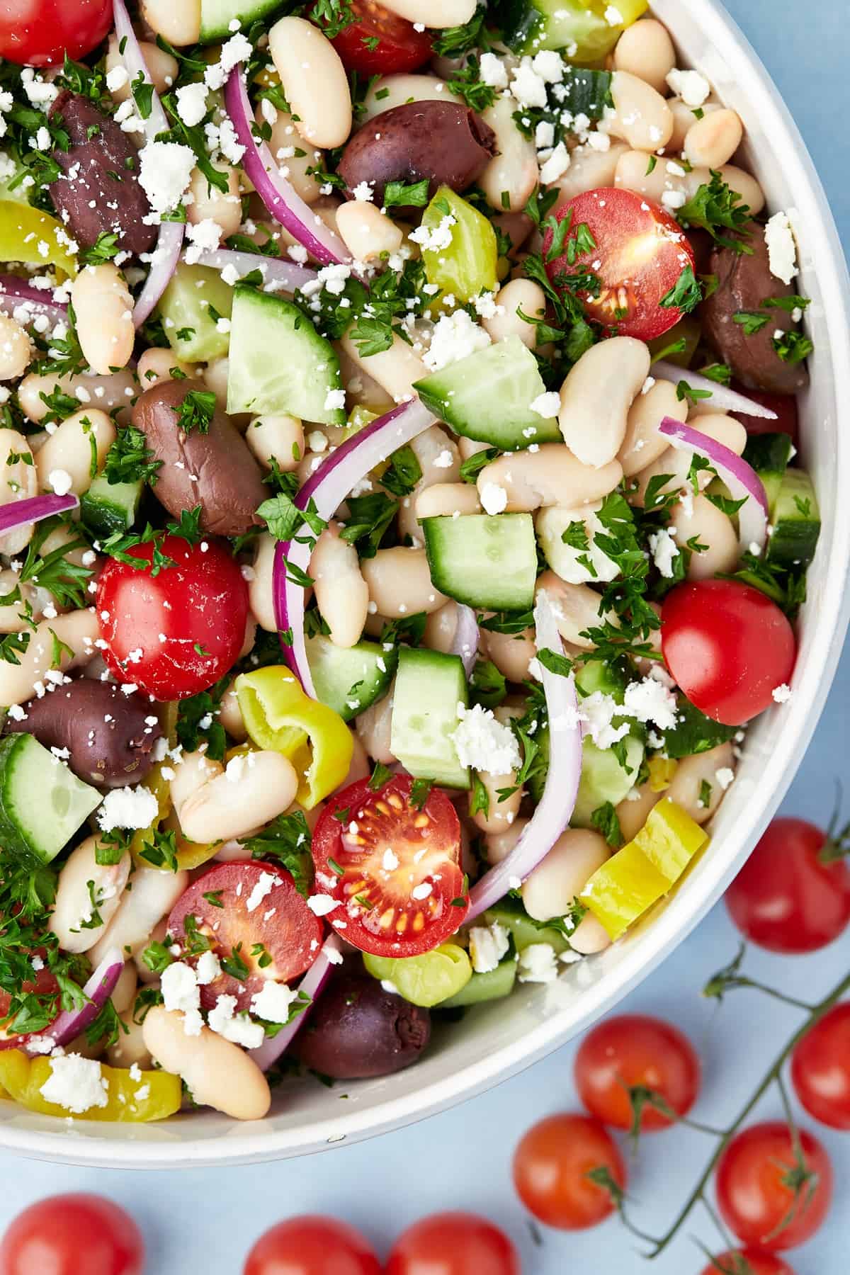 close up de uma tigela de salada de feijao branco com tomates ao lado.