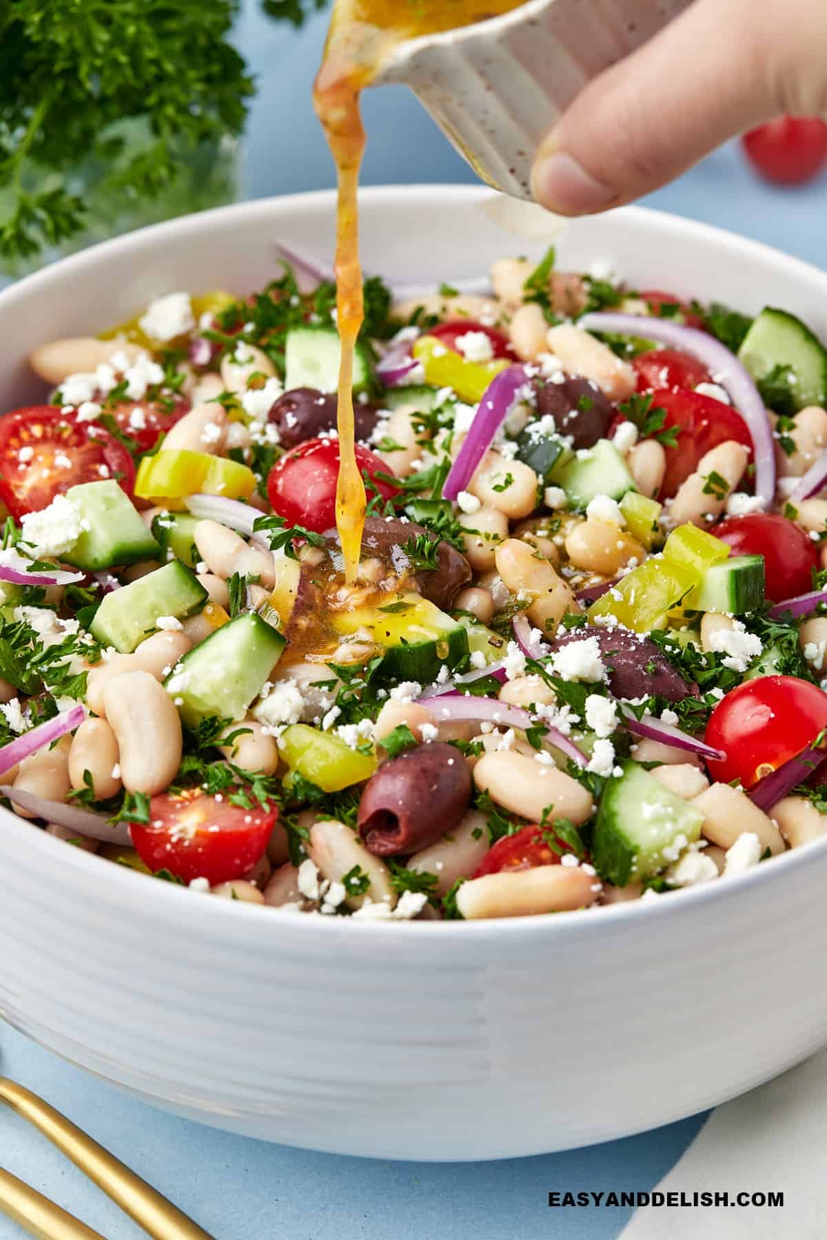 mediterranean salad dressing poured over Mediterranean white bean salad for a no-cook lunch.