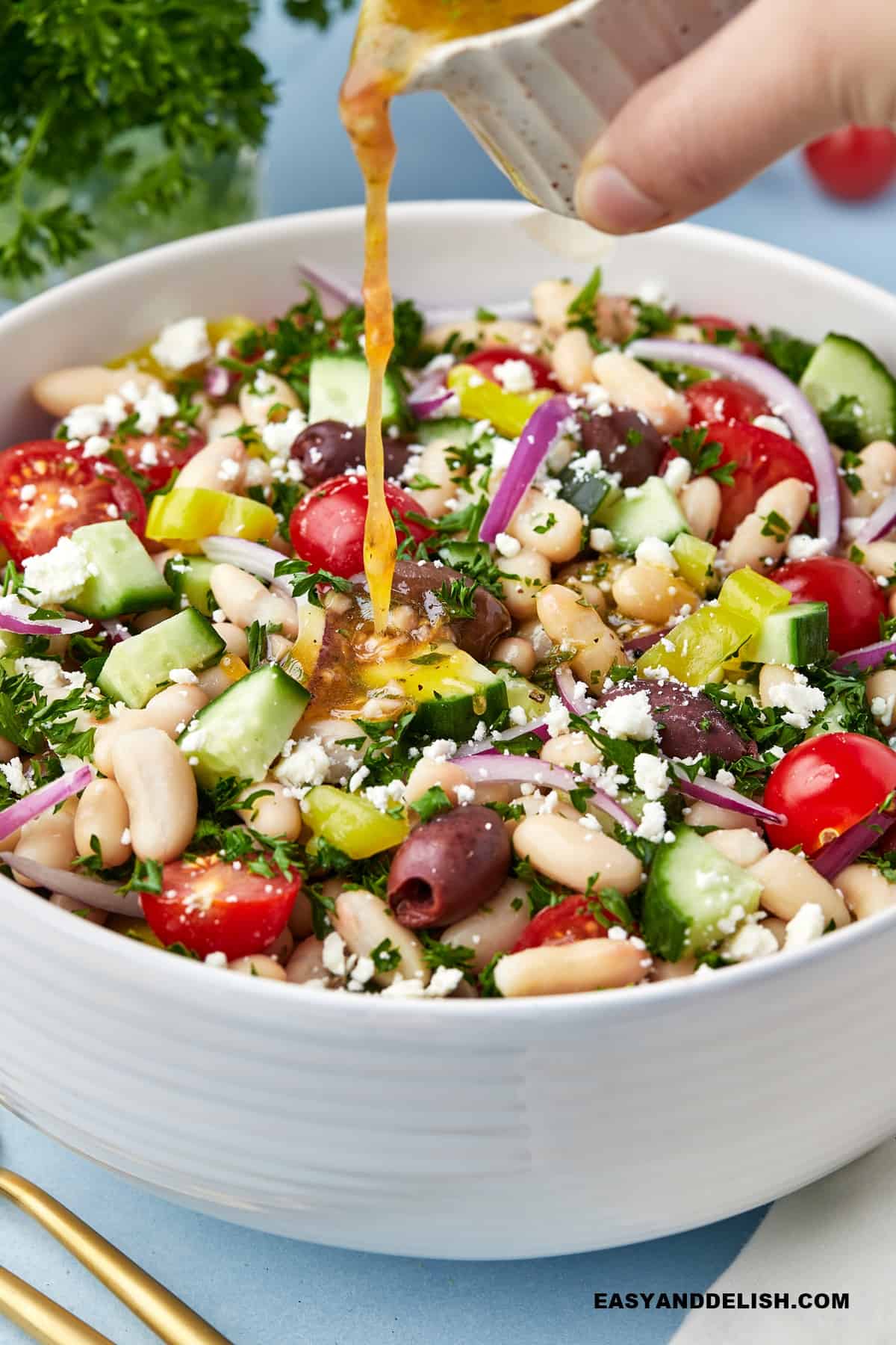 mediterranean salad dressing poured over Mediterranean white bean salad. 