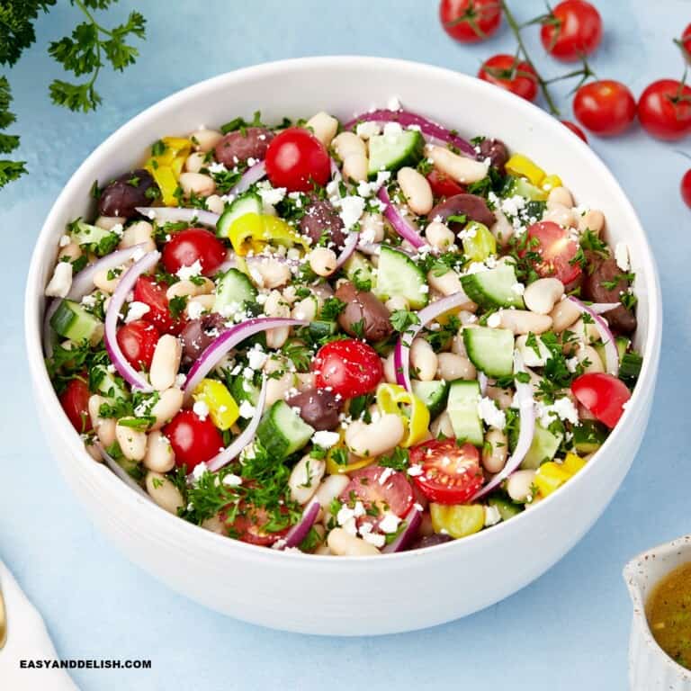 a full bowl of white bean salad with a few ingredients around it.
