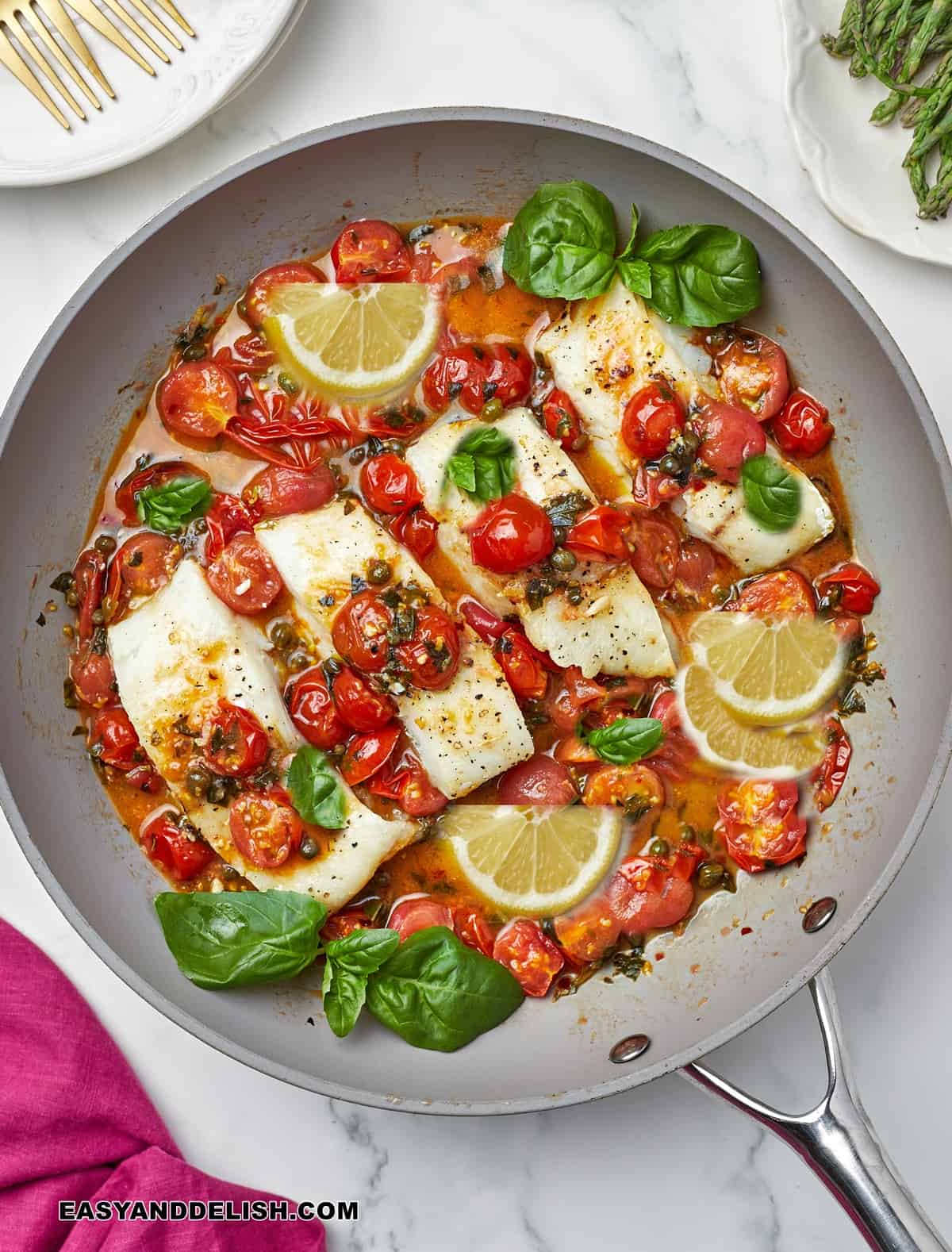 a skillet with Italian baccala in white wine tomato sauce with basil and lemon.