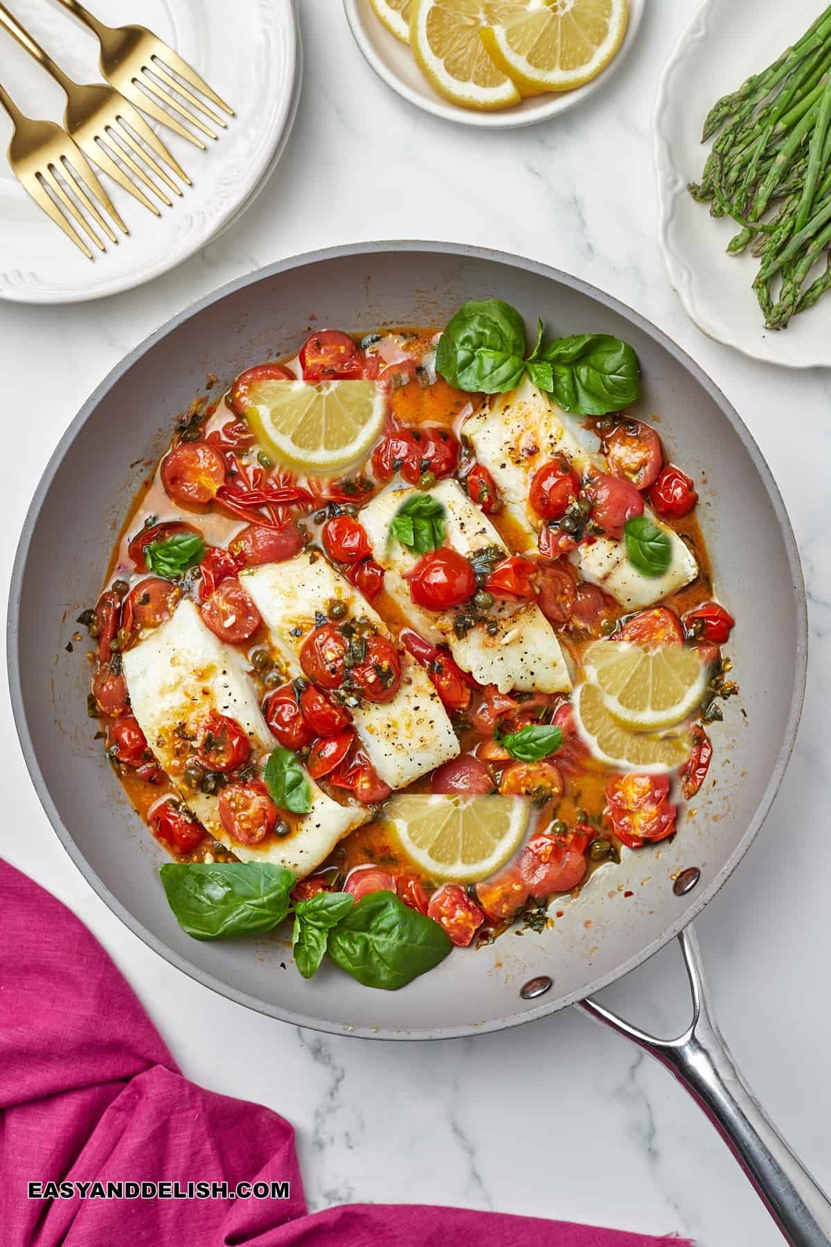 a pan with fish with wine sauce and some garnishes around it.