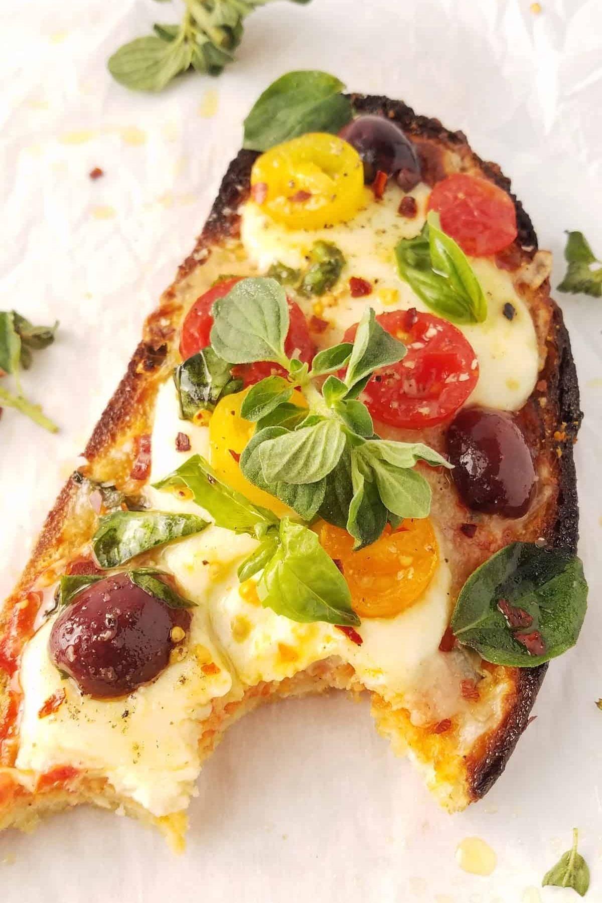 Bitten toast topped with melted mozzarella, cherry tomatoes, Kalamata olives, and basil.