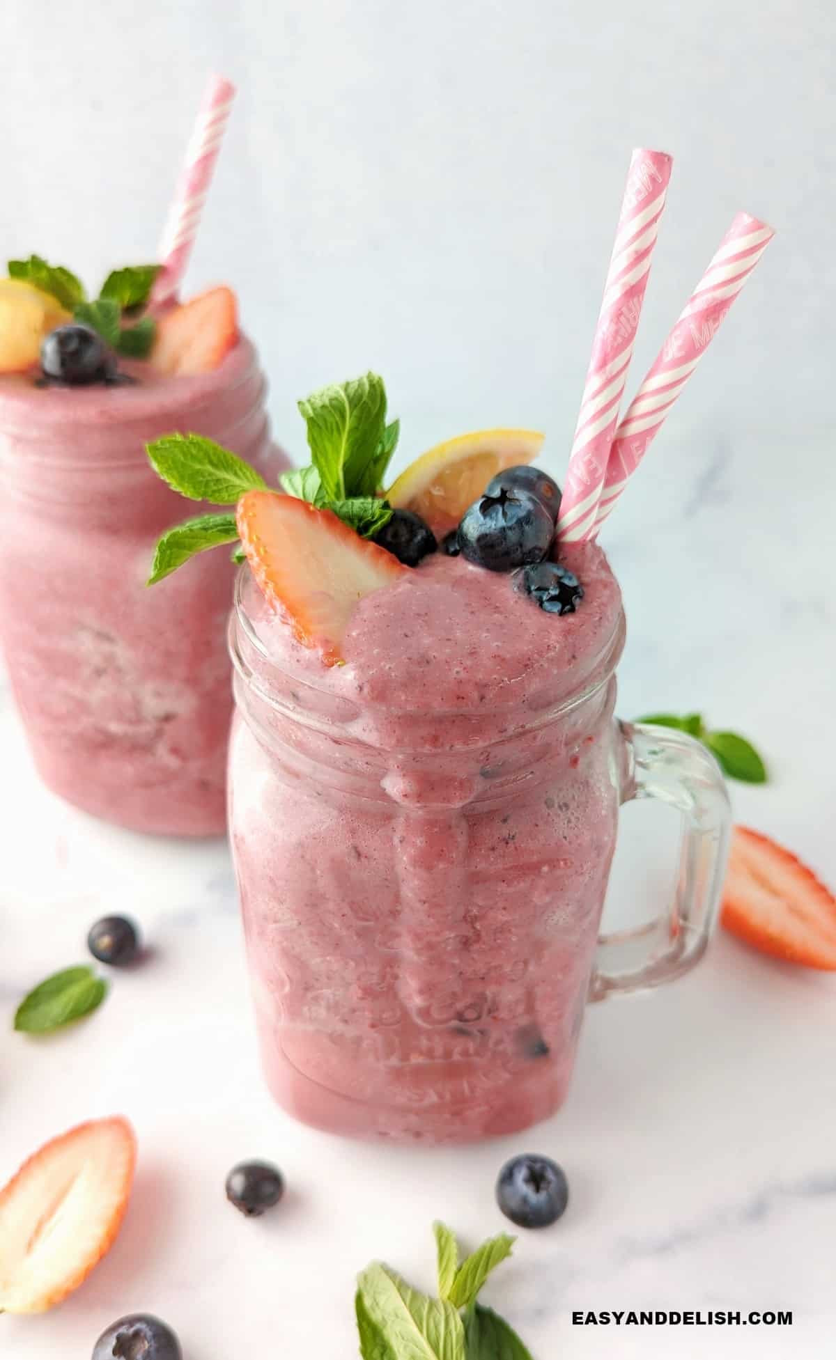 dois copos cheios de vitamina para emagrecer decorada com frutas vermelhas.
