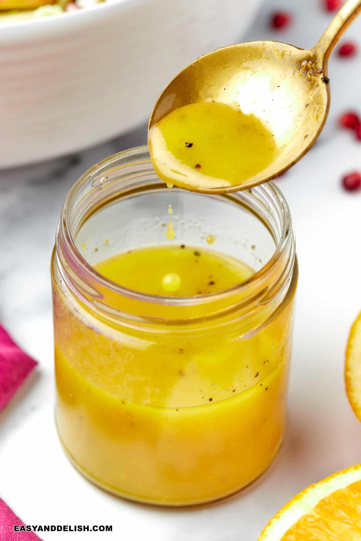 a spoon held over a jar with maple dijon vinaigrette.