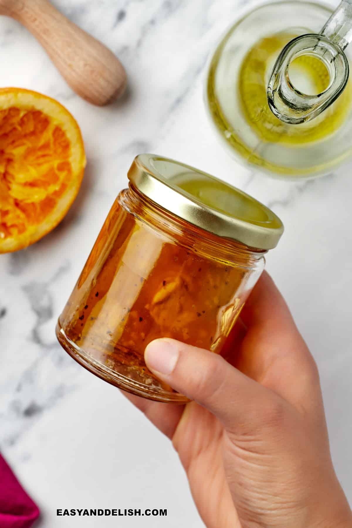 a hand shaking a jar with maple dijon dressing 