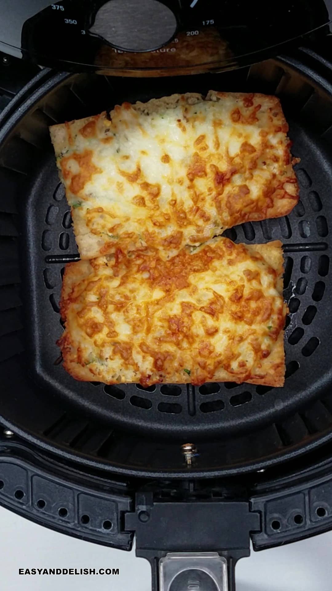 two slices of garlic bread in a air fryer basket.