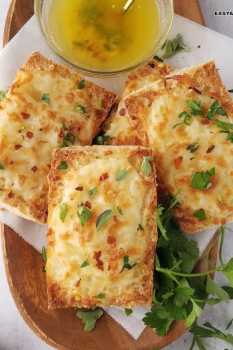 several slices of air fryer garlic bread in a tray with a bowl of melted garlic butter on the side.