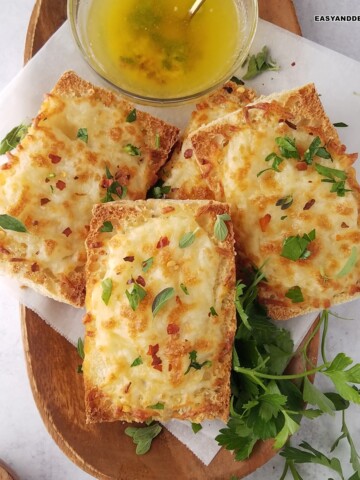 several slices of air fryer garlic bread in a tray with a bowl of melted garlic butter on the side.