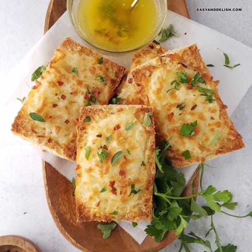 several slices of air fryer garlic bread in a tray with a bowl of melted garlic butter on the side.