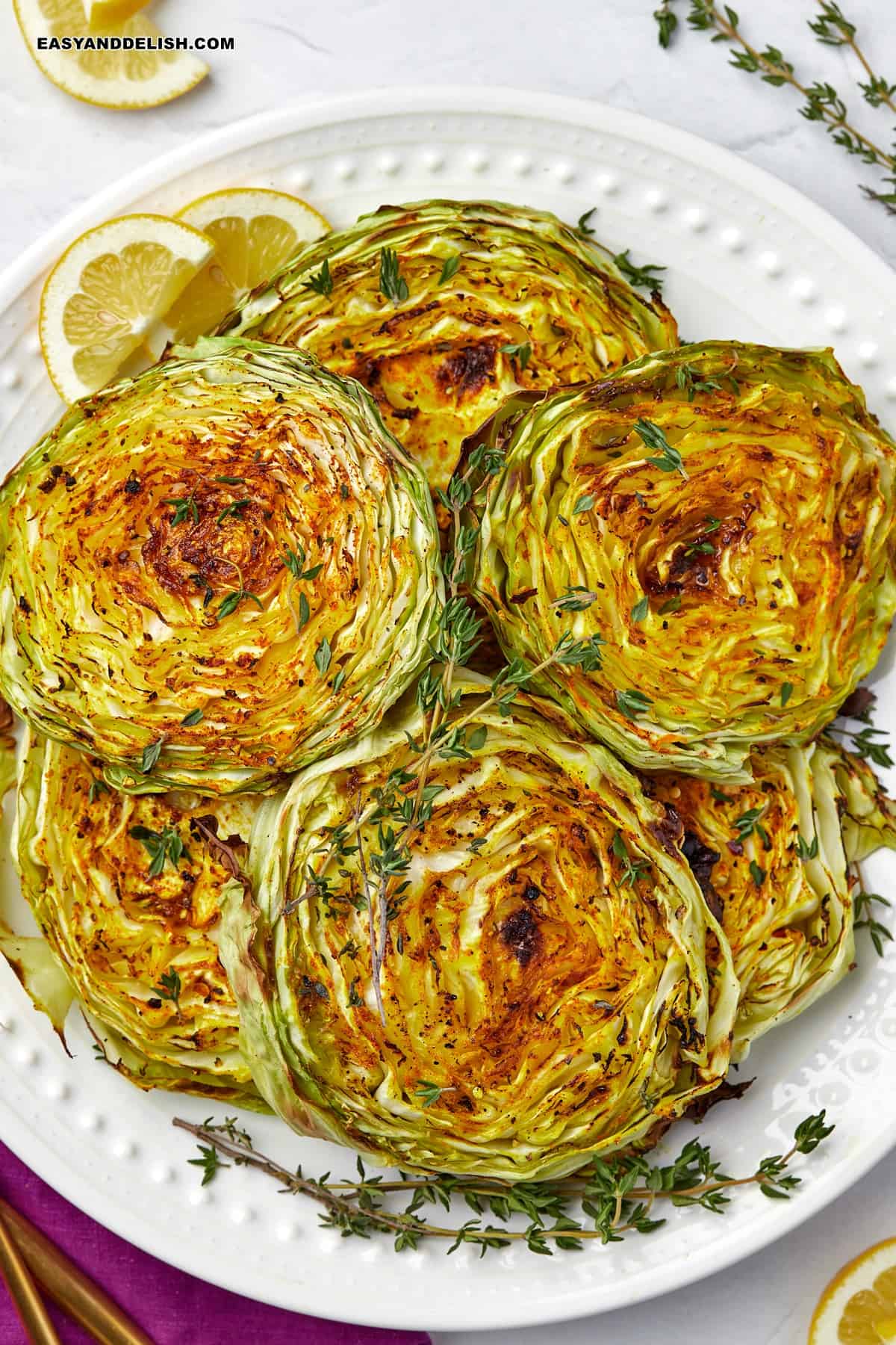 a plate with cabbage steaks and fresh thyme.