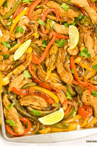 close up of a sheet pan with keto chicken fajitas garlished with lime wedges.
