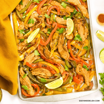 close up of a sheet pan with keto chicken fajitas garlished with lime wedges.