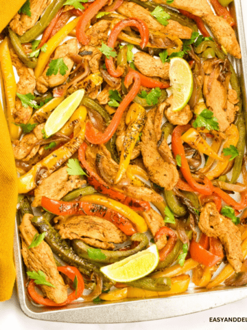 close up of a sheet pan with keto chicken fajitas garlished with lime wedges.