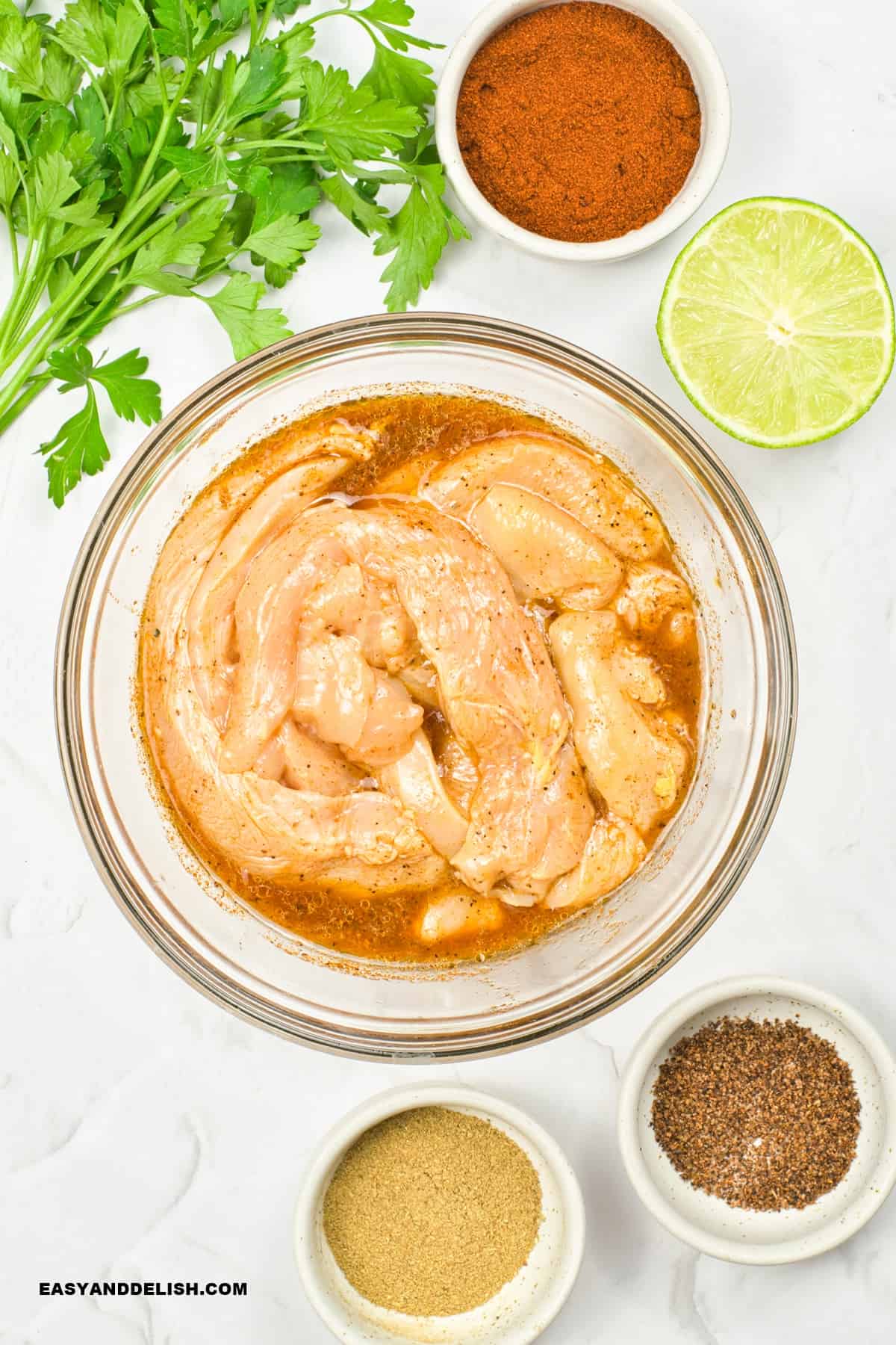 a bowl with chicken strips tossed in a  marinade.