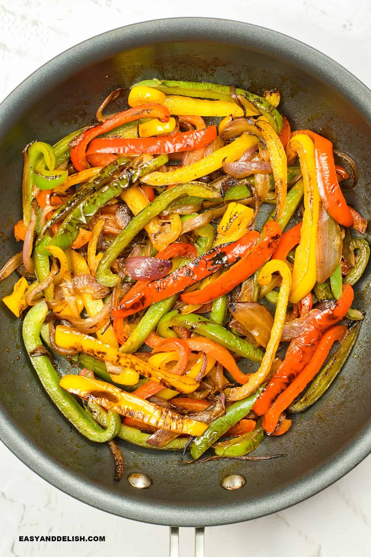 cooked onion adn bell peppers ina  skillet on the stovetop.