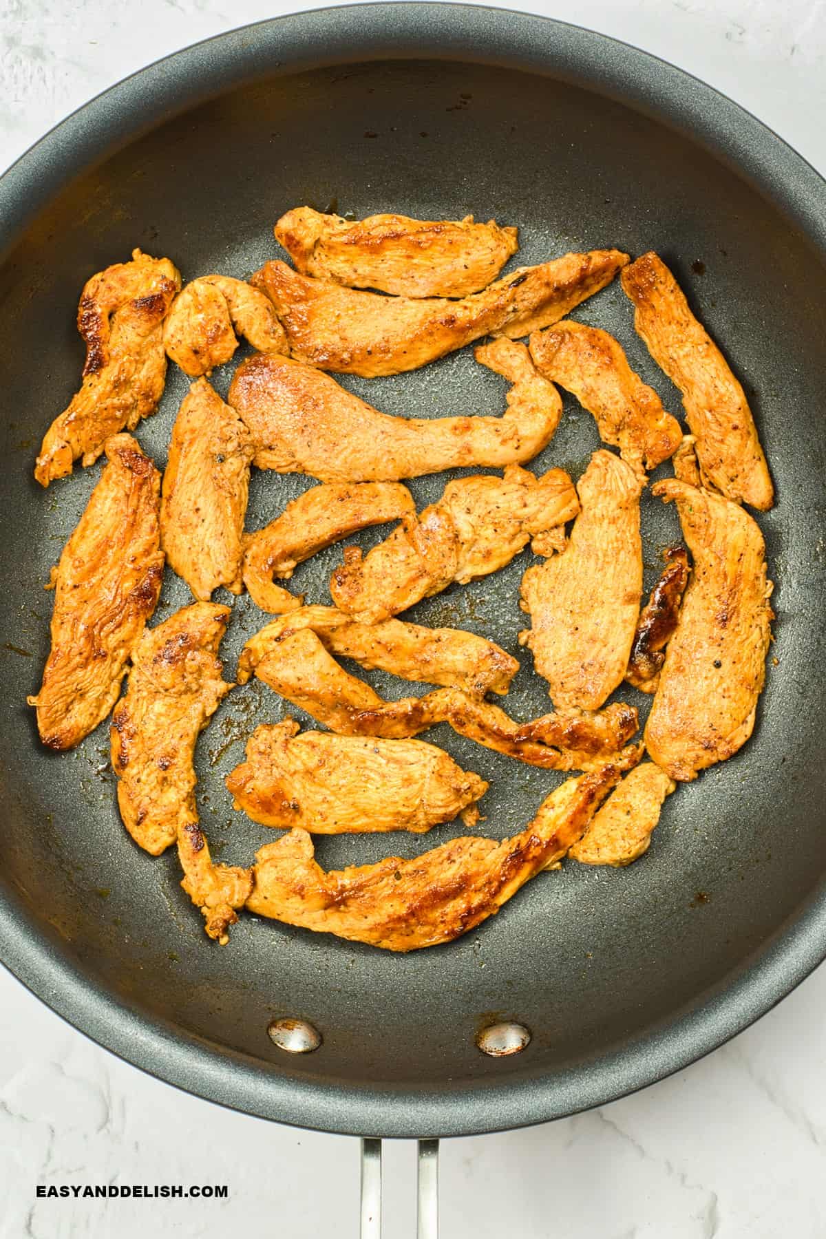 cooked chicken strips in a skillet.