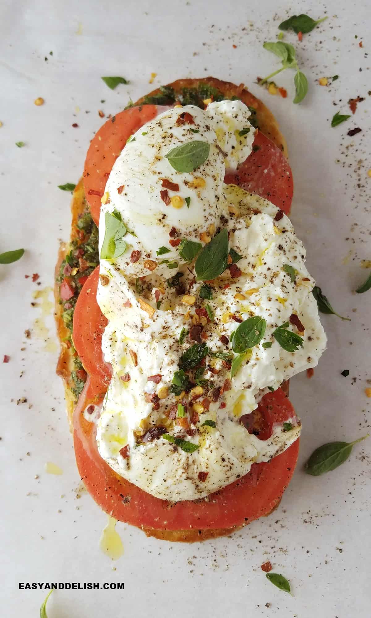 A burrata toast topped with herbs and seasoned with pepper and red pepper flakes.