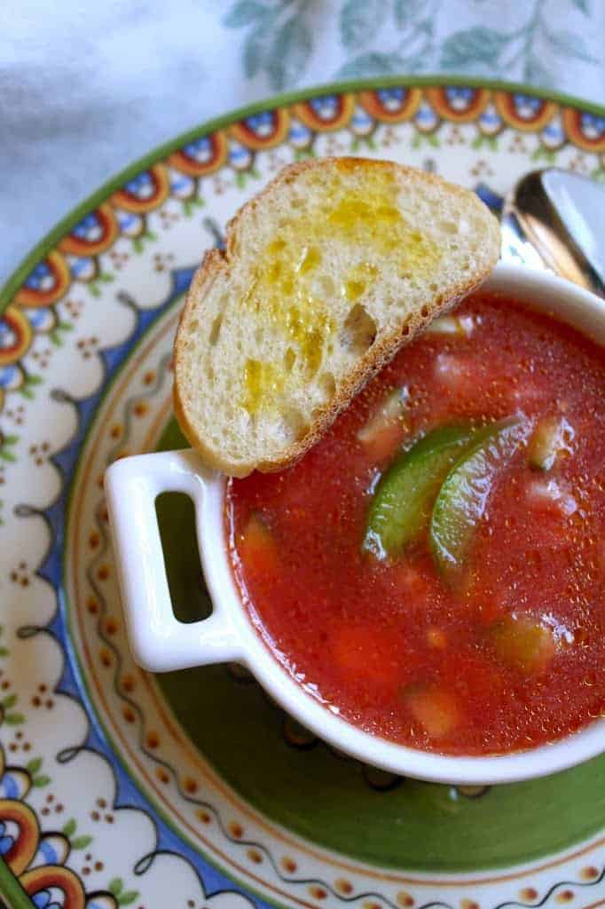 a bowl of chunky gazpacho soup with a toast on top.