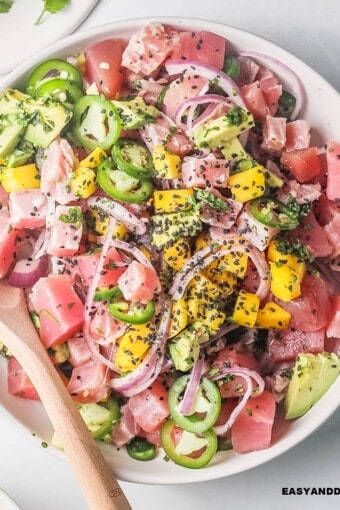 close up of tuna ceviche in a bowl with a spoon on the side.