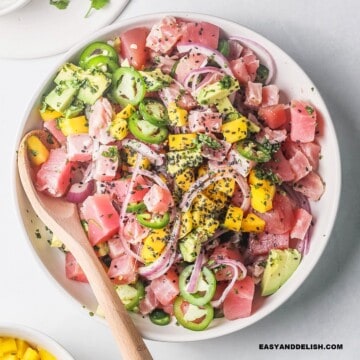 close up of tuna ceviche in a bowl with a spoon on the side.