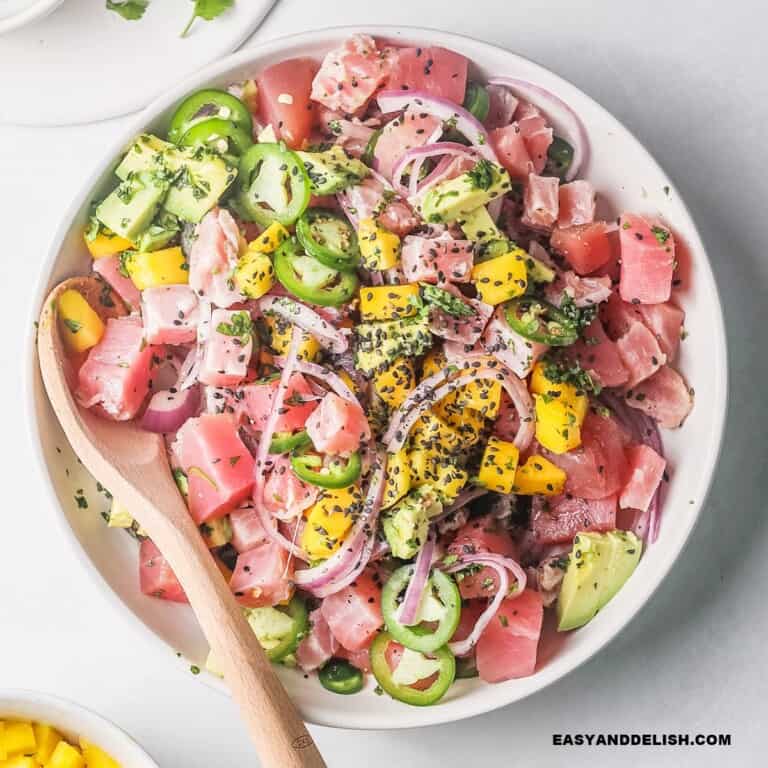 close up of tuna ceviche in a bowl with a spoon on the side.