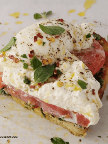 close up of half burrata toast drizzled with EVOO.