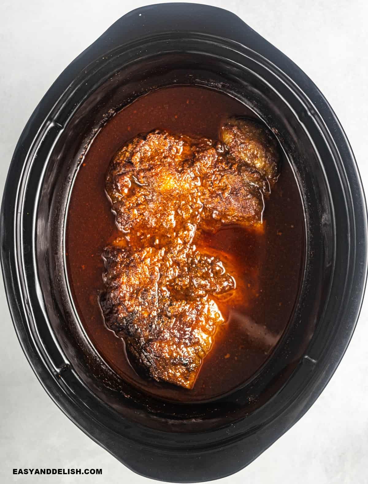 slow cooked beef brisket and its juices in a crockpot.