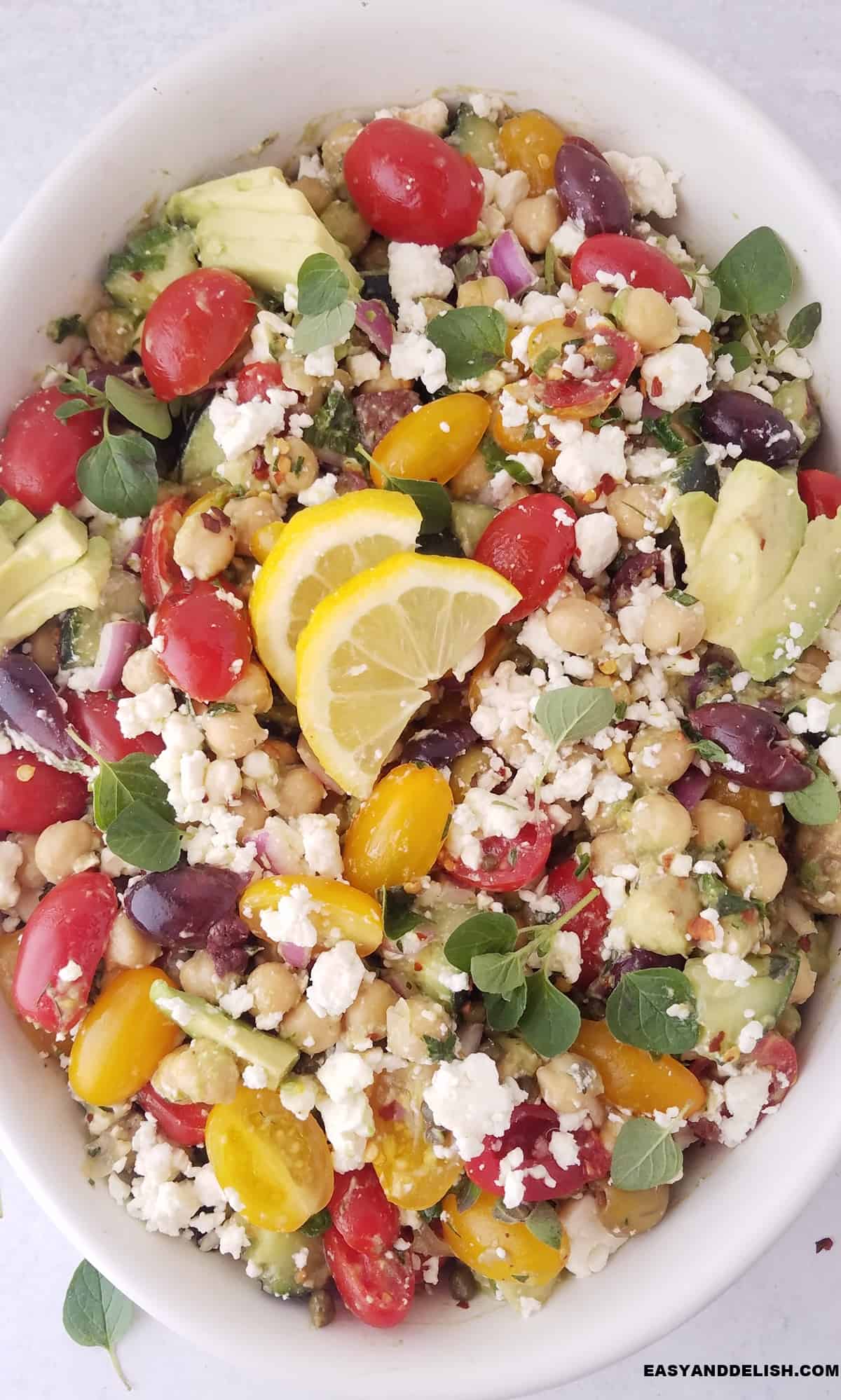 closeup of cucumber chickpea salad in a bowl with lemon slices on top.