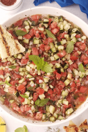 A bowl of shirazi salad with a mini toast on the side.