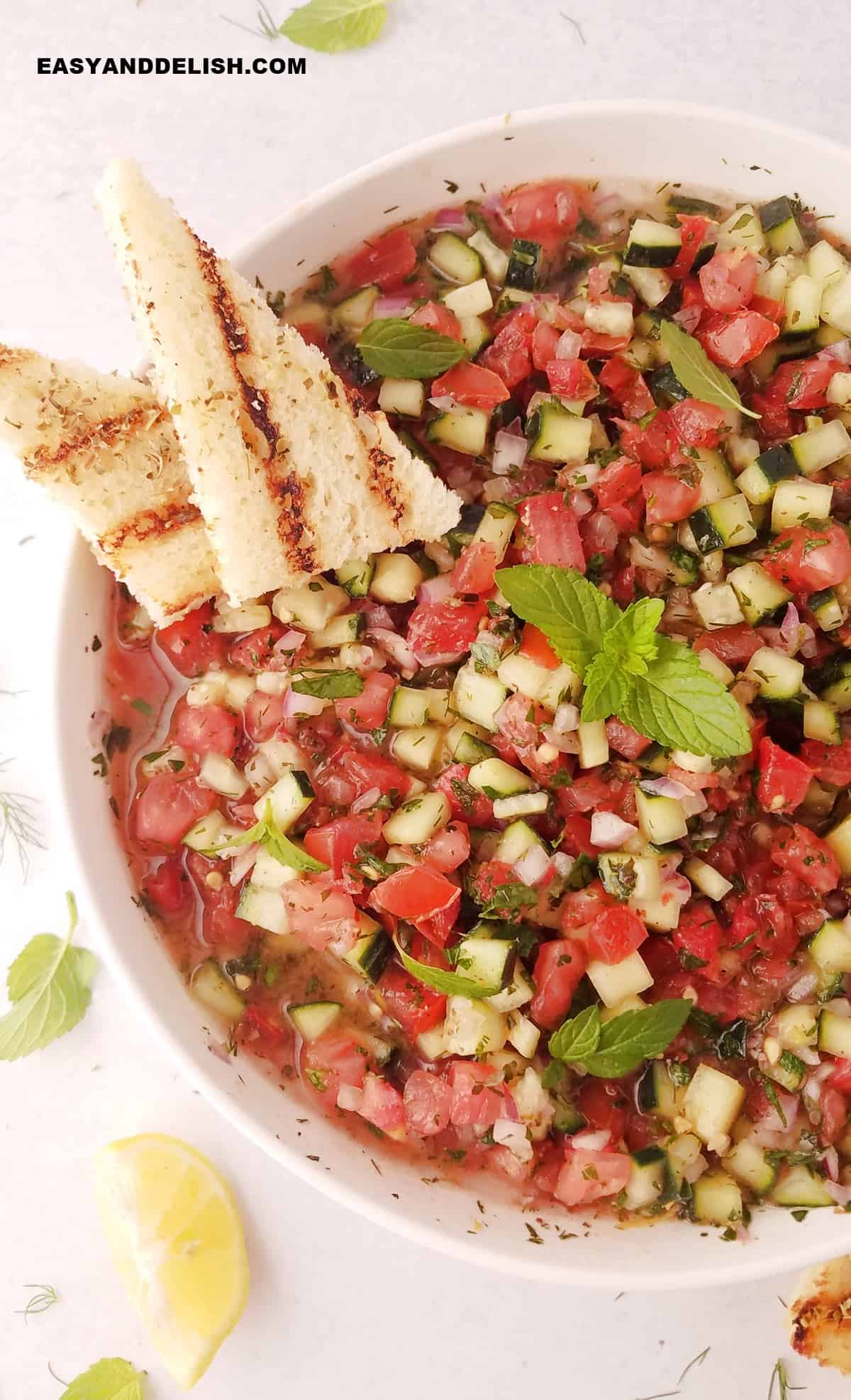 Close up of a bowl of salad-e shirazi with two toasts on the side.