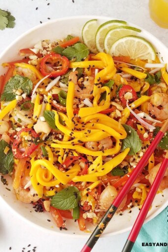 close up image of a bowl of Thai mango salad with chopsticks on the side.