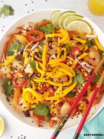 close up image of a bowl of Thai mango salad with chopsticks on the side.