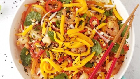 close up image of a bowl of Thai mango salad with chopsticks on the side.