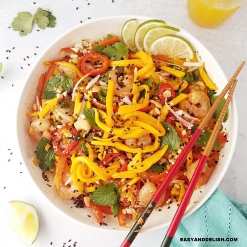 close up image of a bowl of Thai mango salad with chopsticks on the side.