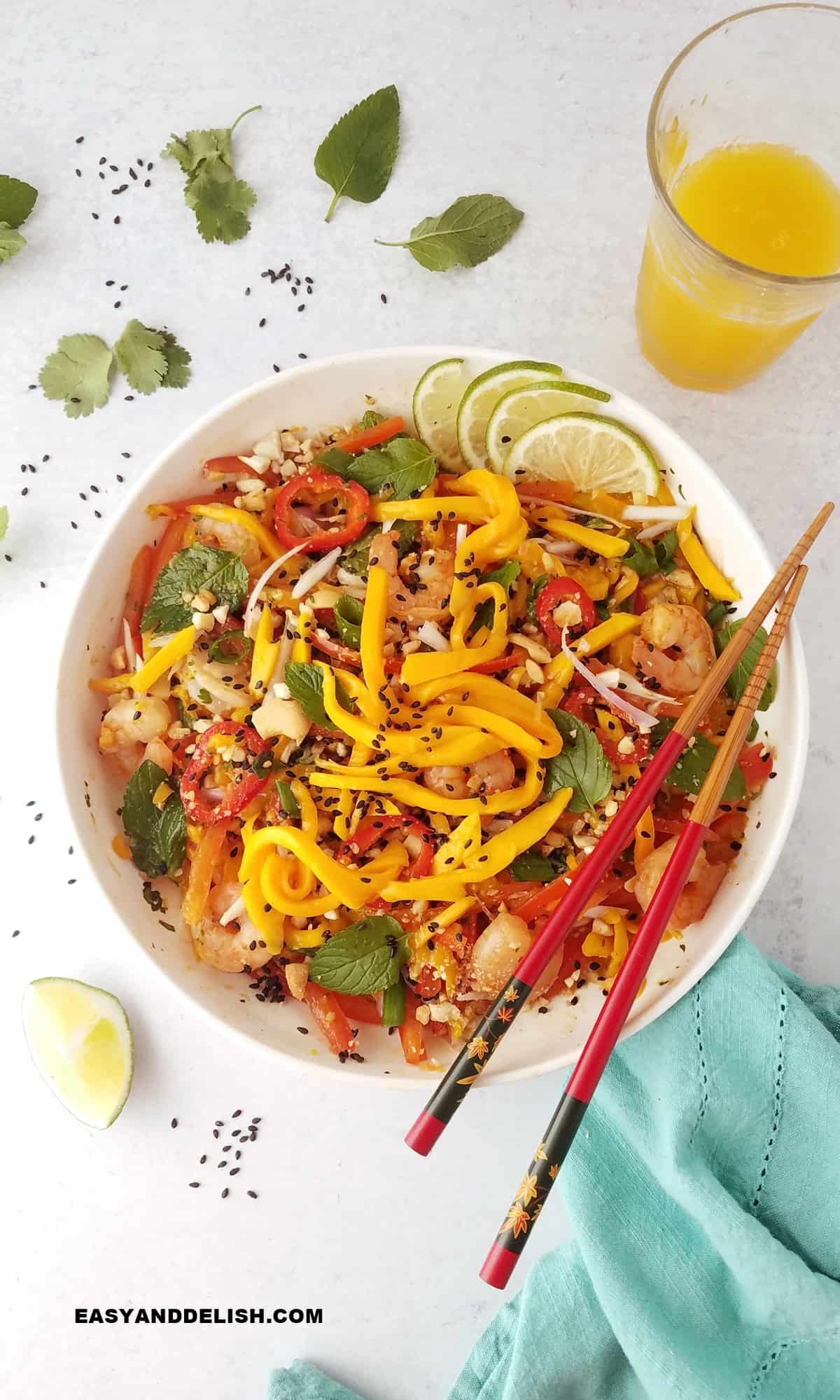 thani mango salad served ina  bowl with some juice glass on the background.