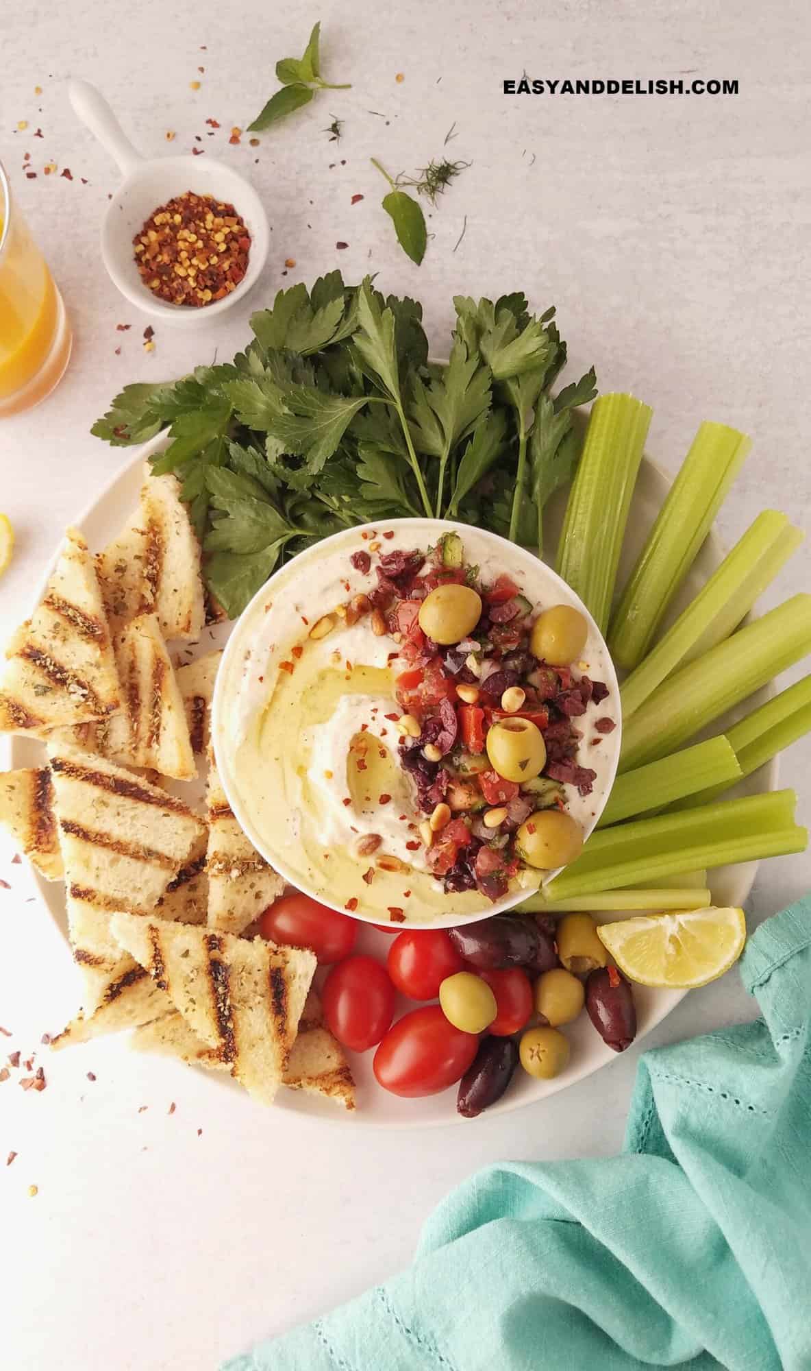 a platter with veggies and mini toasts plus a bowl of ricotta dip.