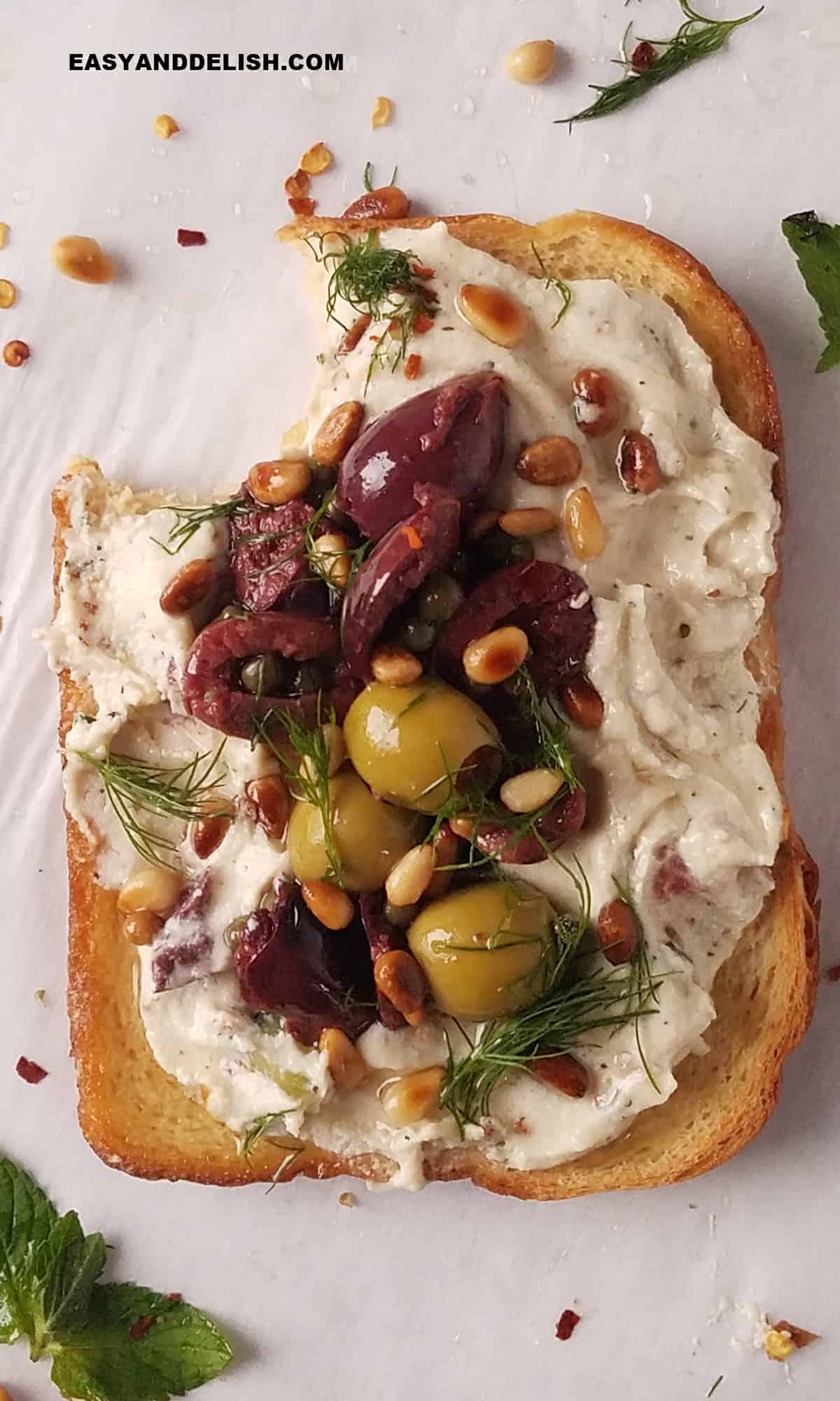 Whipped ricotta toast with olives and pine nuts.