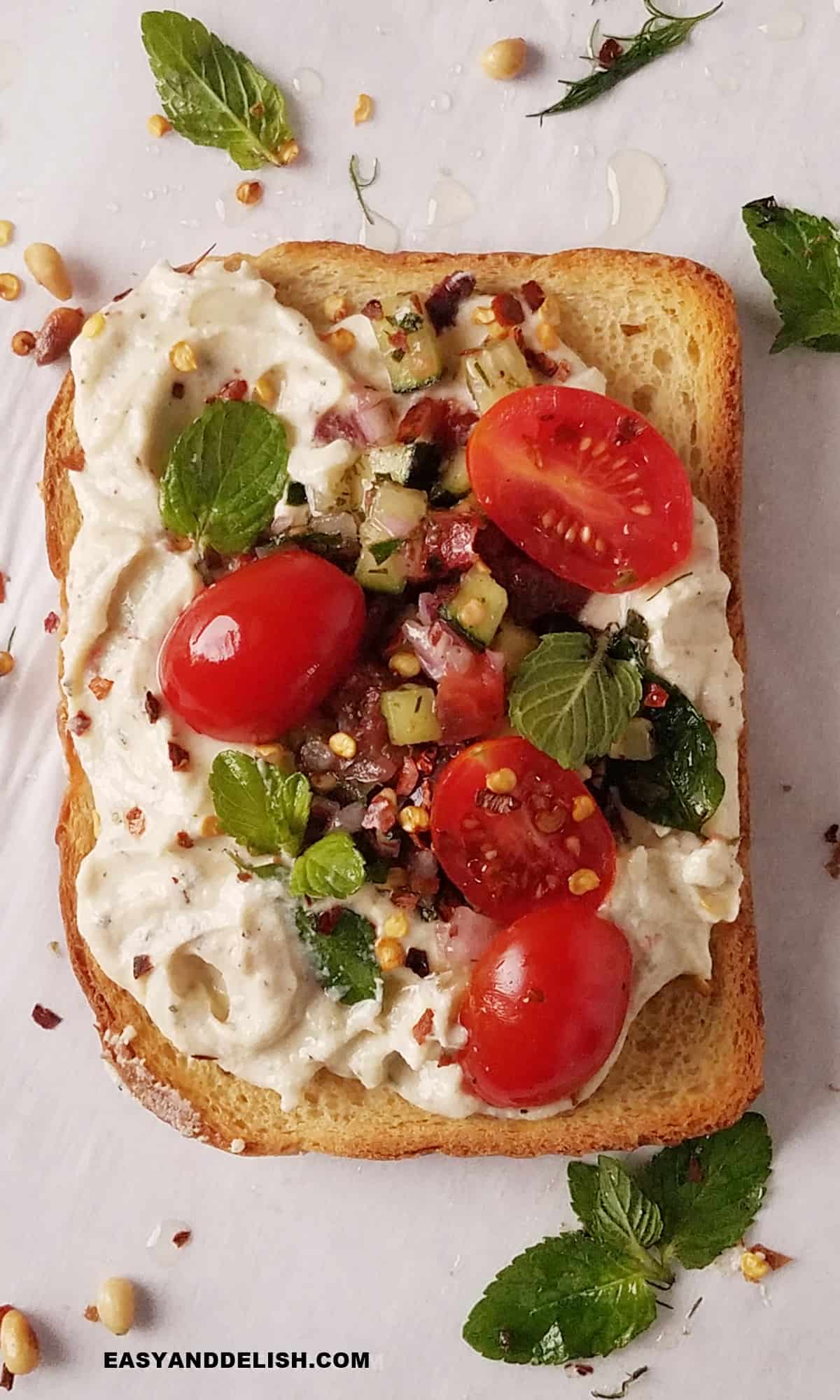 ricotta toast with tomatoes, fresh herbs, and pine nuts.