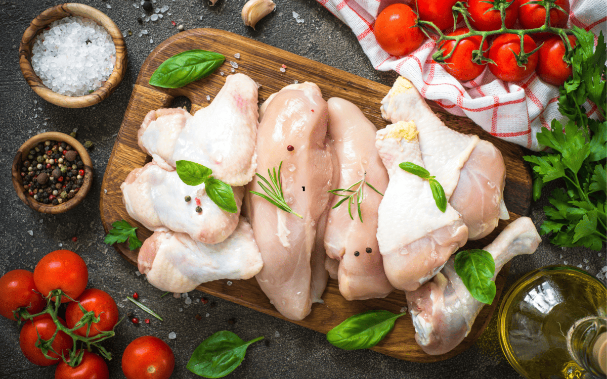 raw chicken cuts and some veegtables on a table.