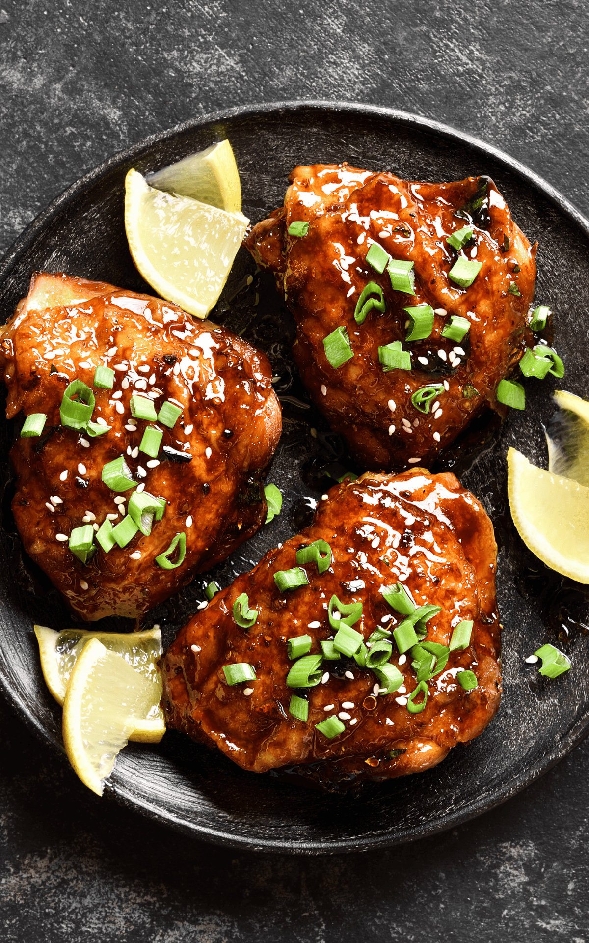 a plate with slow cooker chicken thighs and lemon wedges as one of our 50 easy healthy crockpot meals for dinner. 