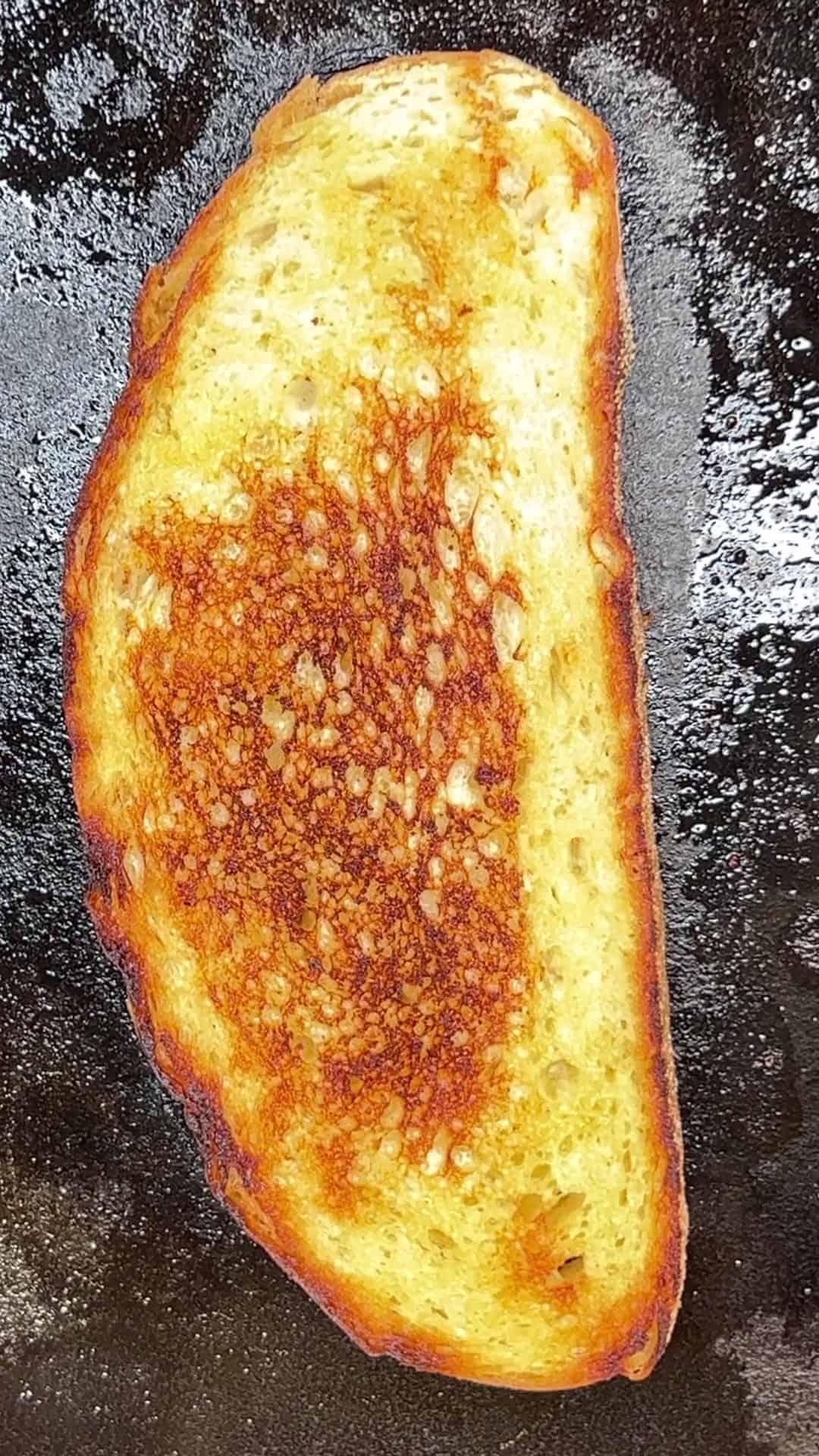 Toasted sourdough bread slice on a griddle.