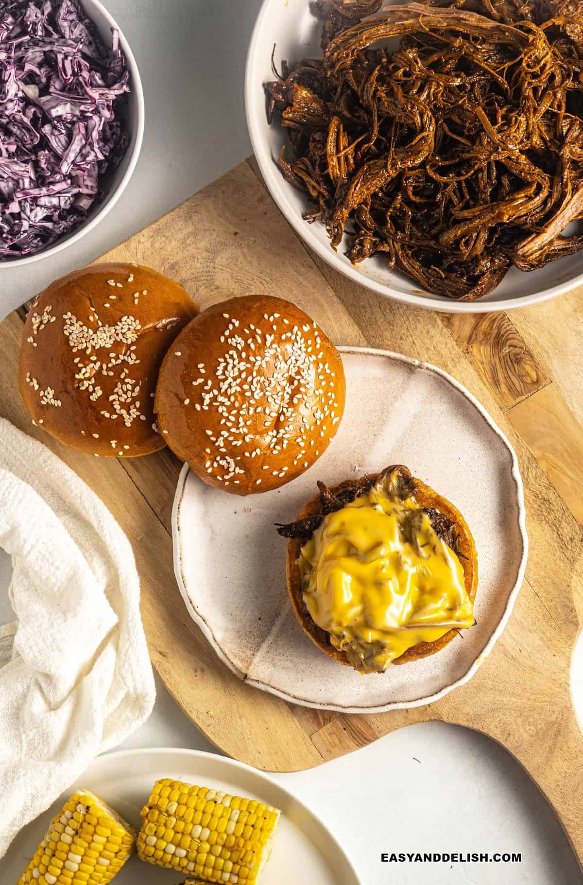 shredded beef and melted cheese in a burger bun with sides around it.